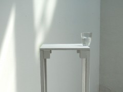 Un baso de agua puesto sobre el borde de una mesa